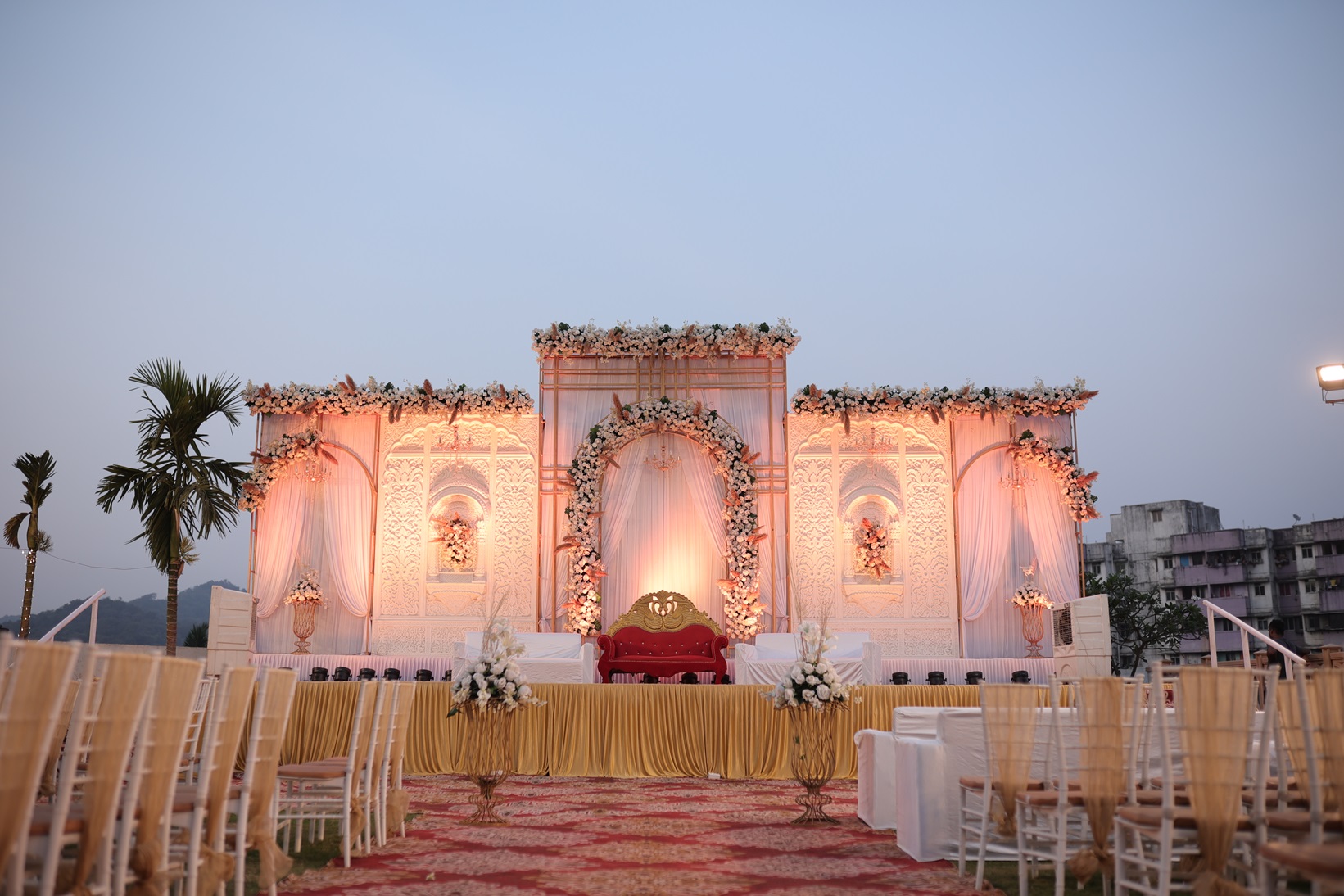 Outdoor reception setup on a sky deck lawn with vibrant flower and a beautiful view.